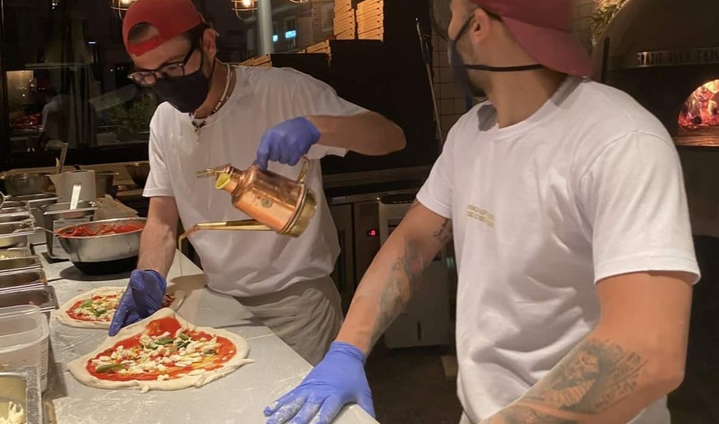 Dos pizzaiolos cocinando pizza napoletana con arte